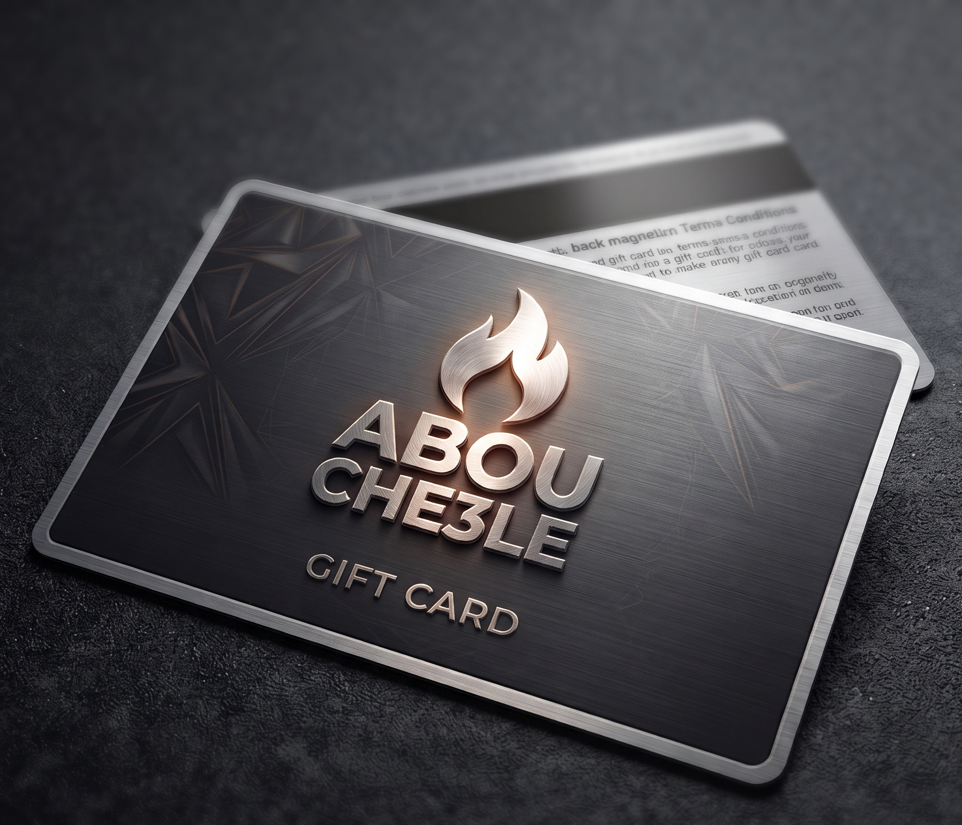 A metallic gift card with a brushed dark gray finish, featuring the brand name 'ABOU CHE3LE' in raised silver lettering beneath a stylized flame logo. The card is shown at an angle on a dark textured surface, with a second card partially visible behind it.