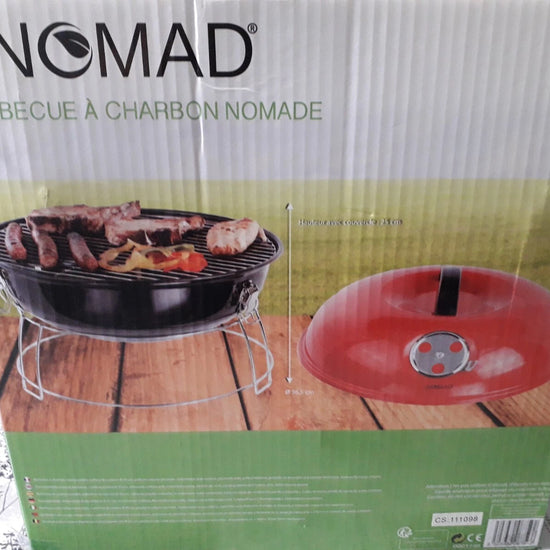 BE NOMAD charcoal barbecue box packaging showing a black round grill with food on the grate and a red lid on a wooden surface, photographed in a real indoor setting.