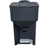 A black electric fuel grinder or grinder machine with a hopper on top, standing on a concrete floor in front of a building entrance.